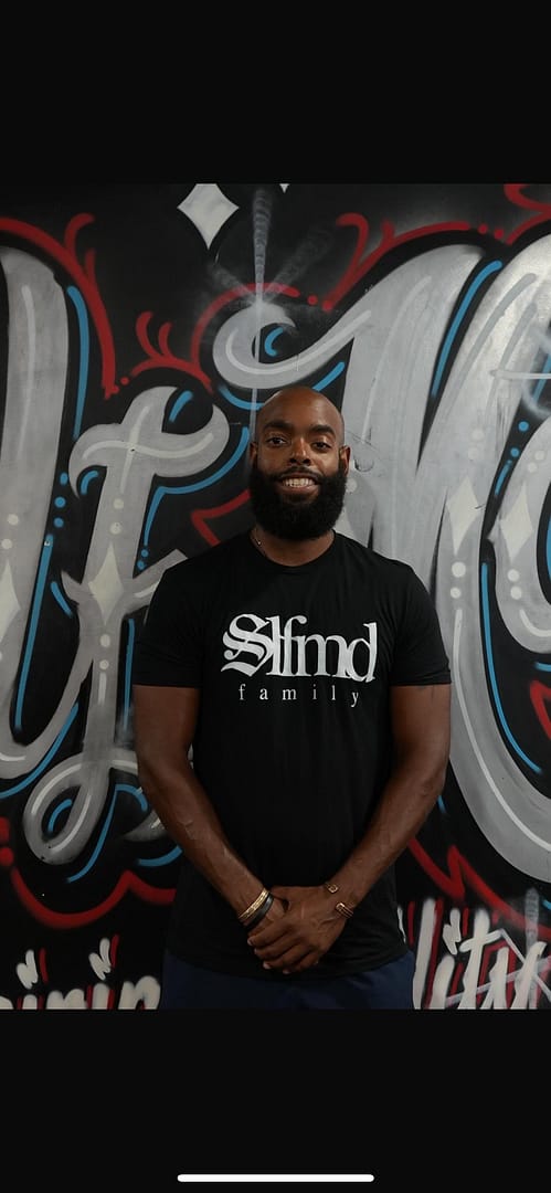 A photo of Benjamin Moore, a former collegiate athlete and NASM-certified personal trainer, smiling and engaging with a client in a gym setting.