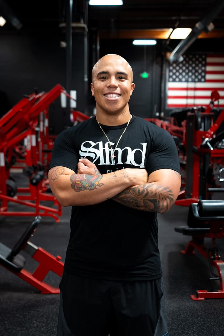 A photo of Alundas Havens, a personal trainer with a warm smile, coaching a client during a workout session in a bright and inviting gym.